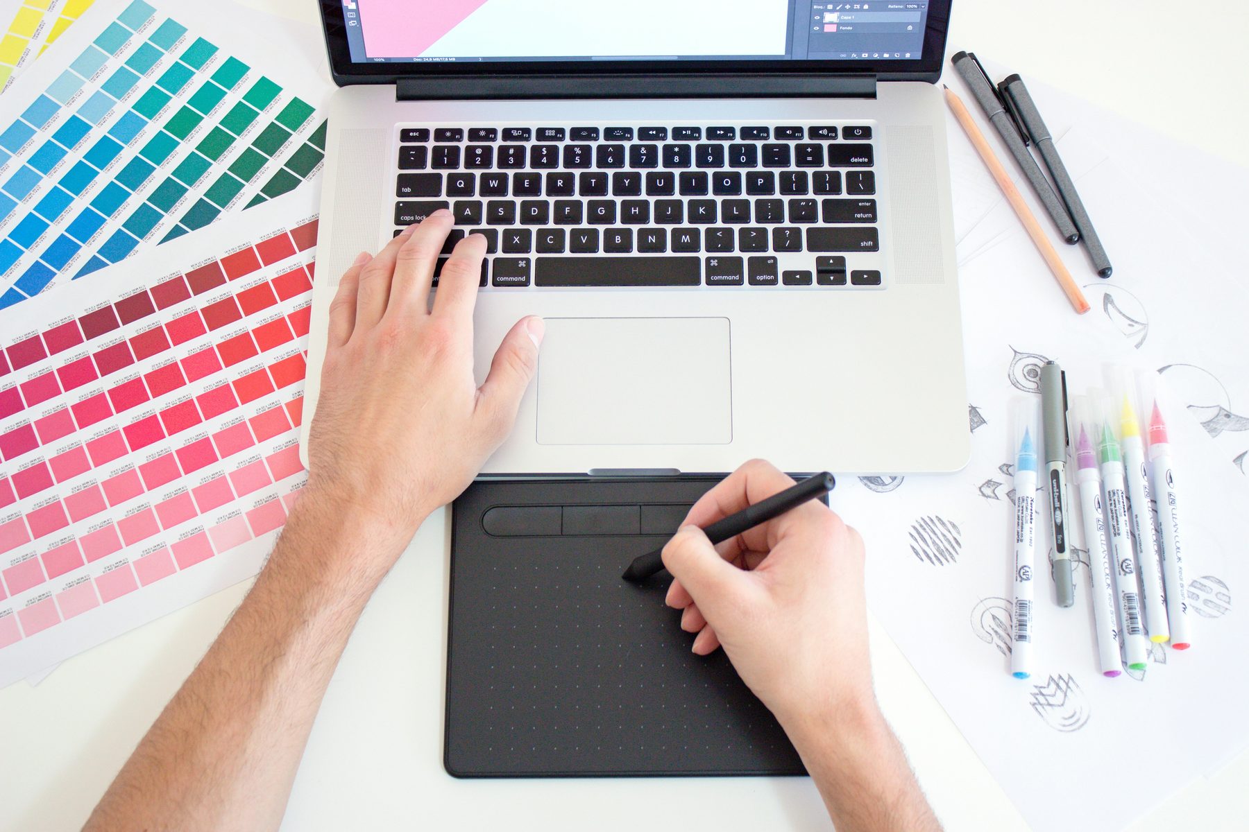 Graphic designer working with a drawing tablet and color references